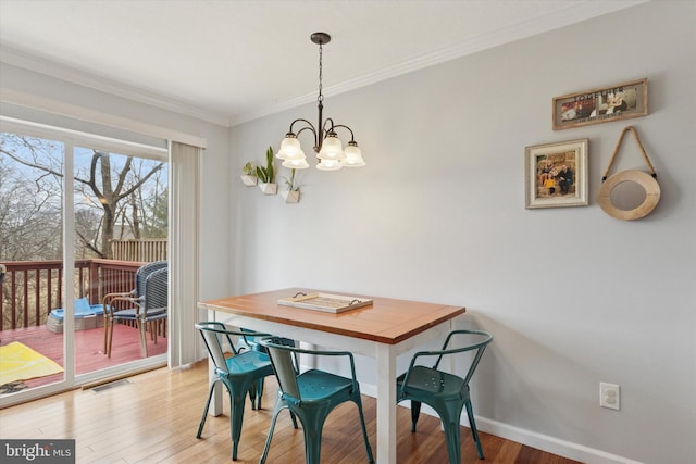 dining space with visible vents, a notable chandelier, ornamental molding, wood finished floors, and baseboards