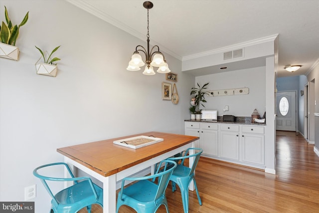 dining space with light wood-style flooring, visible vents, a chandelier, and ornamental molding