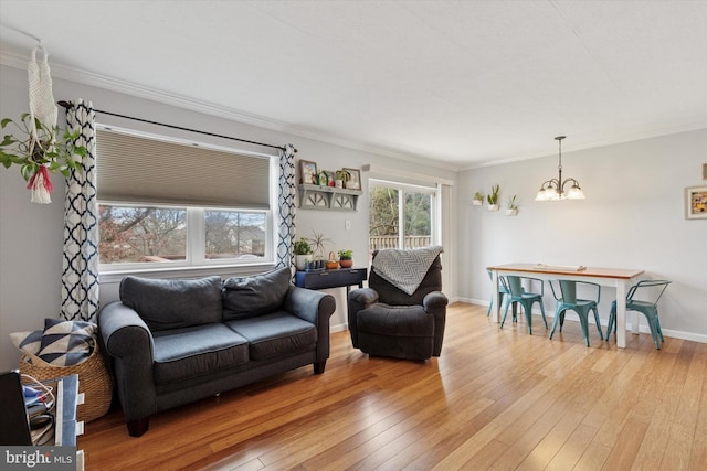 living area with a chandelier, baseboards, light wood-style floors, and ornamental molding