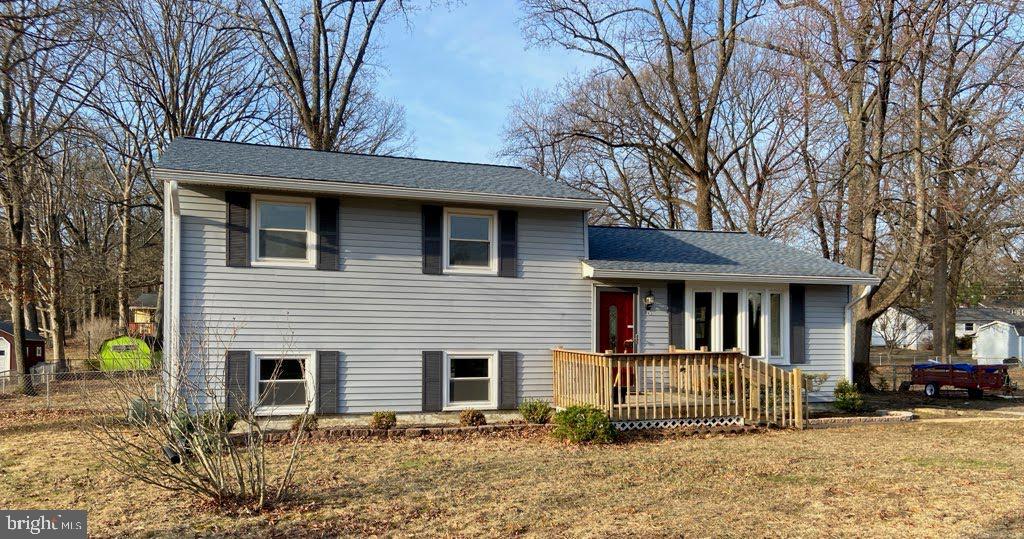 tri-level home with a shingled roof, a front yard, and fence