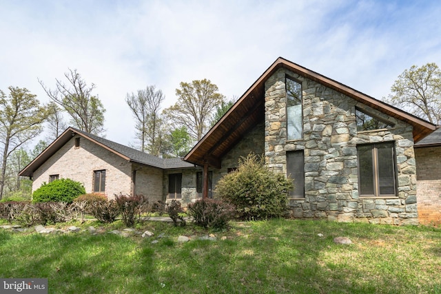 view of front facade with brick siding, a front lawn, and stone siding