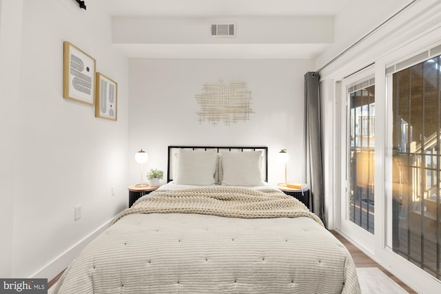 bedroom featuring access to exterior, wood finished floors, baseboards, and visible vents