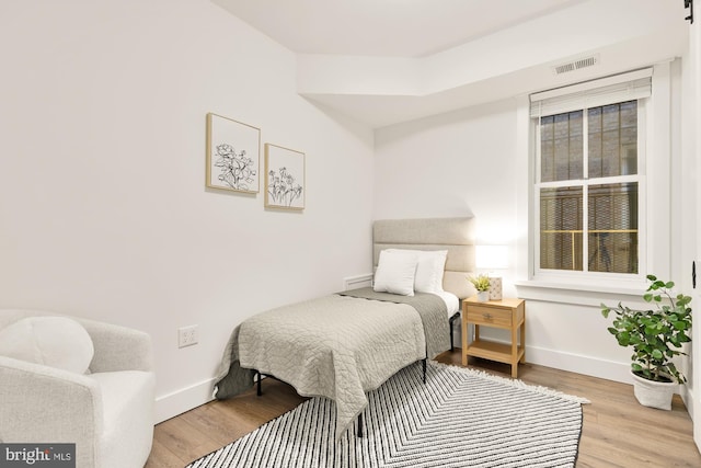 bedroom featuring visible vents, baseboards, and wood finished floors