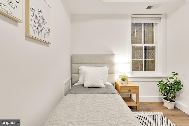 bedroom with wood finished floors, visible vents, and baseboards