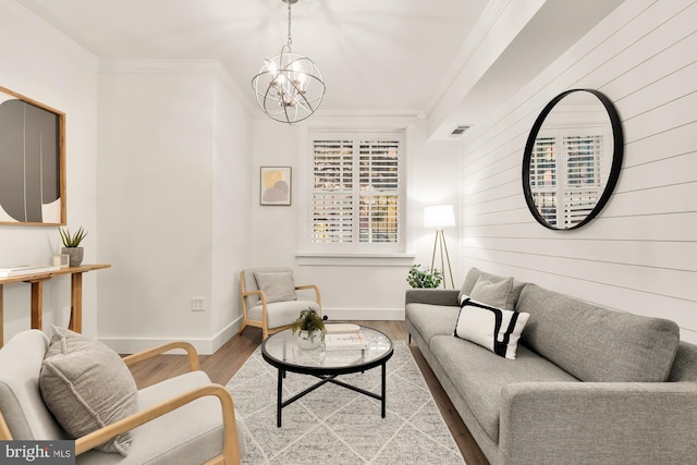 living area featuring wood finished floors, baseboards, a chandelier, and ornamental molding