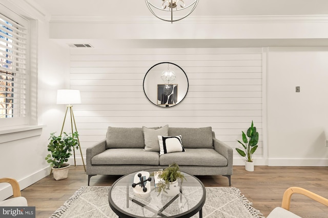 living area featuring a healthy amount of sunlight, crown molding, and wood finished floors