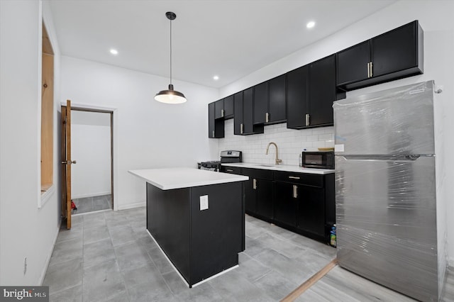 kitchen with a sink, stainless steel appliances, dark cabinetry, and light countertops