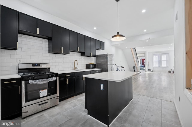 kitchen featuring a center island, light countertops, appliances with stainless steel finishes, dark cabinetry, and a sink