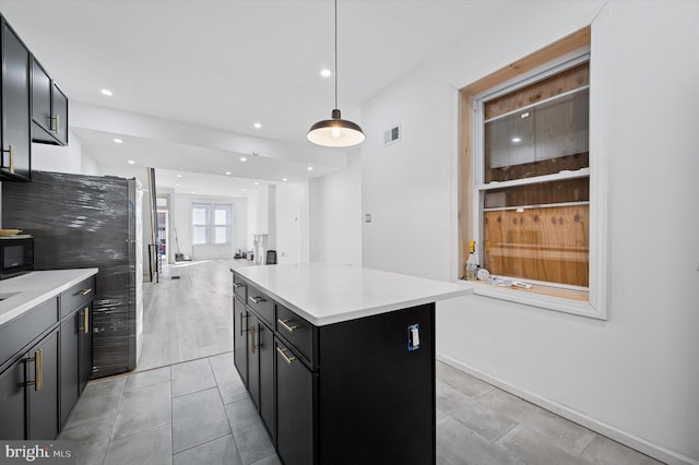 kitchen featuring visible vents, a kitchen island, open floor plan, and light countertops