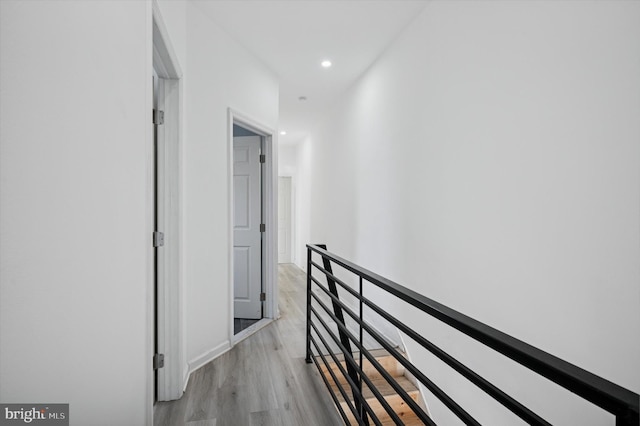 hall with recessed lighting, an upstairs landing, and light wood finished floors