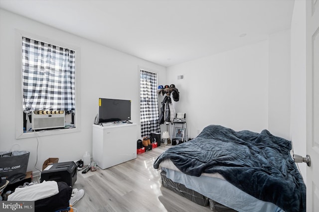 bedroom featuring cooling unit, visible vents, and wood finished floors