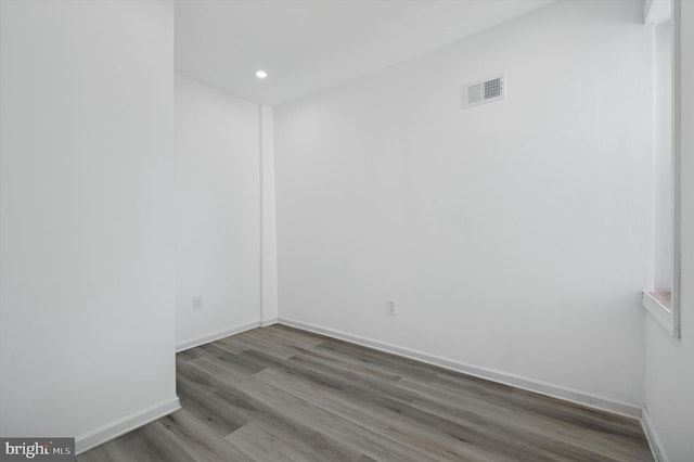 unfurnished room featuring recessed lighting, wood finished floors, visible vents, and baseboards