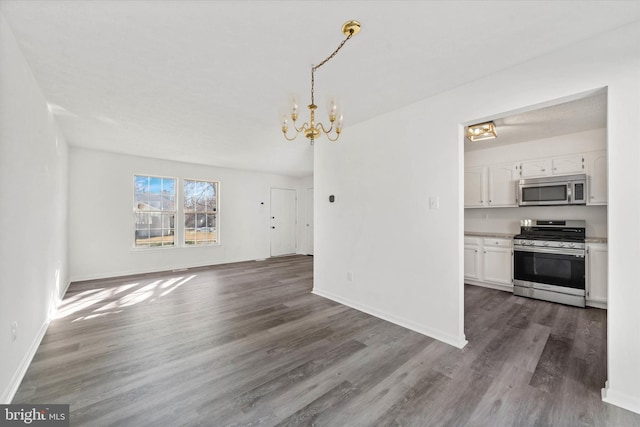 unfurnished living room with baseboards, wood finished floors, and a chandelier