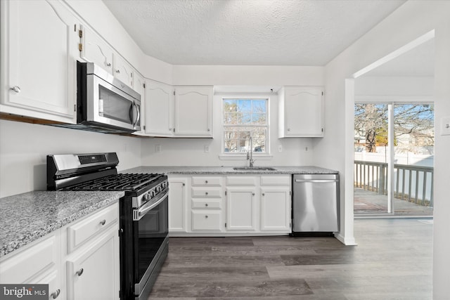 kitchen featuring dark wood-type flooring, a sink, a textured ceiling, appliances with stainless steel finishes, and white cabinets