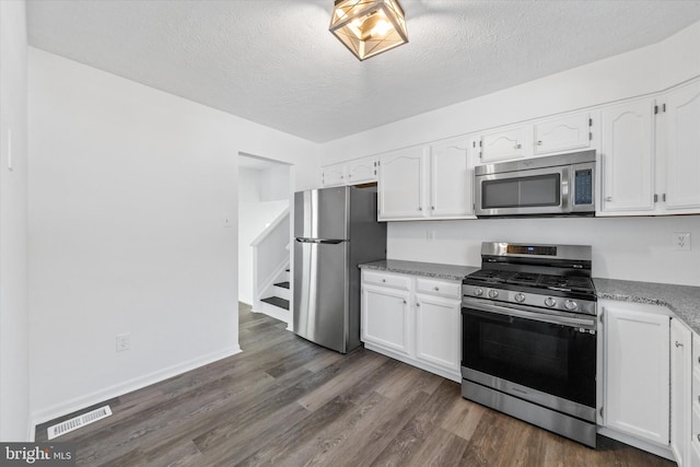 kitchen featuring visible vents, a textured ceiling, white cabinetry, appliances with stainless steel finishes, and dark wood-style flooring