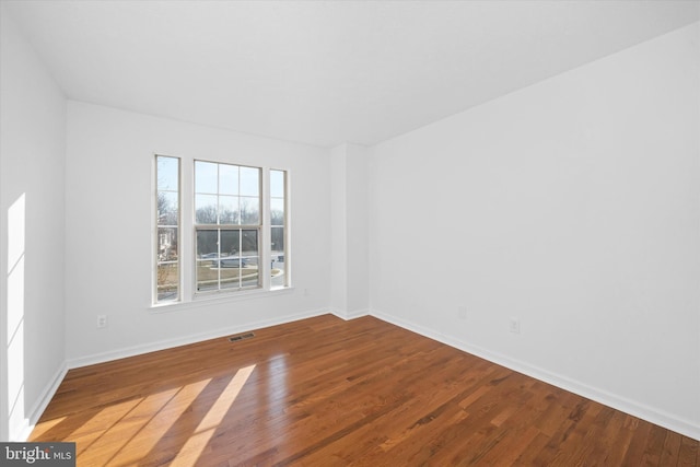 unfurnished room with visible vents, baseboards, and wood finished floors