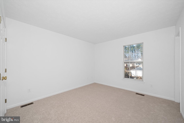 carpeted spare room featuring baseboards and visible vents