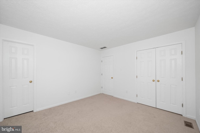 unfurnished bedroom with carpet, visible vents, and a textured ceiling