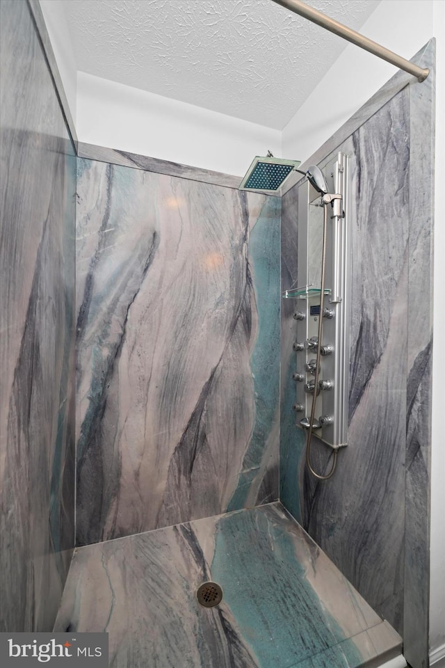 bathroom with a marble finish shower and a textured ceiling