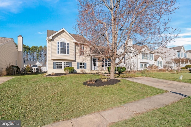 split level home featuring a residential view, concrete driveway, and a front lawn