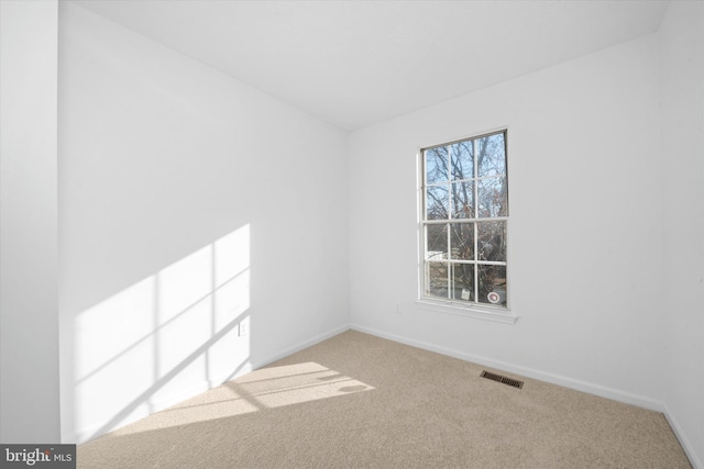 carpeted spare room with plenty of natural light, baseboards, and visible vents