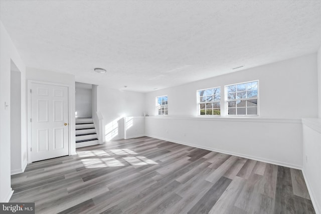 spare room with stairway, a textured ceiling, and wood finished floors