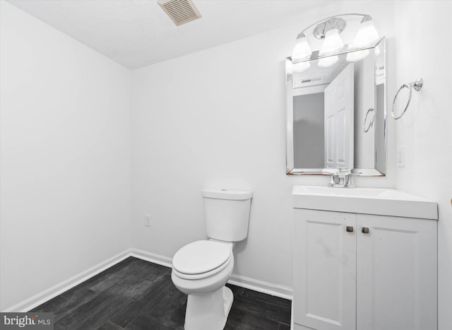 bathroom with visible vents, baseboards, toilet, wood finished floors, and vanity