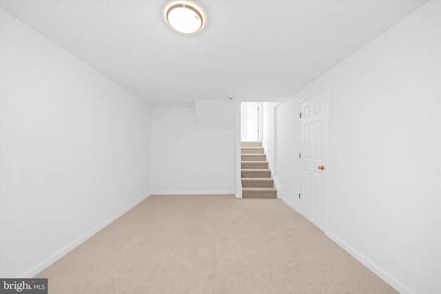 finished below grade area with light colored carpet, stairs, and baseboards