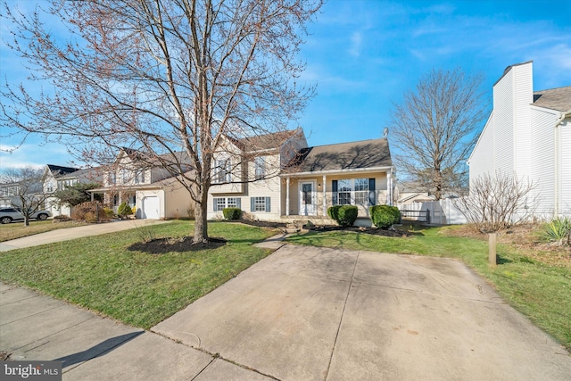 split level home featuring a garage, concrete driveway, a front yard, and fence