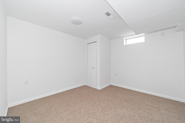 basement featuring visible vents, carpet flooring, and baseboards