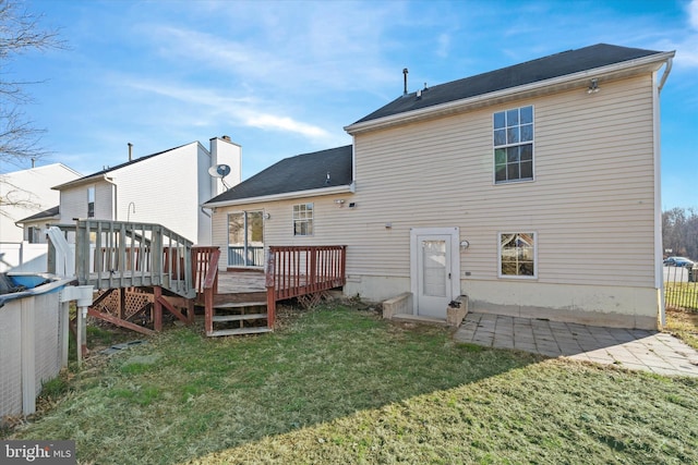 rear view of property featuring a patio area, a lawn, a deck, and fence