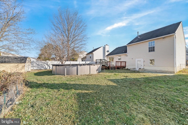 view of yard with a covered pool, a deck, and fence