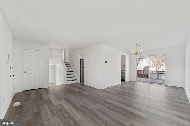 unfurnished living room with visible vents, baseboards, a chandelier, stairs, and wood finished floors