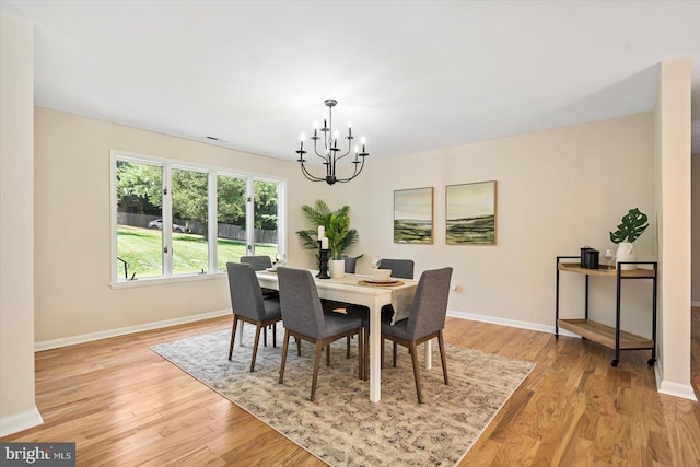 dining area featuring baseboards, a notable chandelier, and light wood finished floors