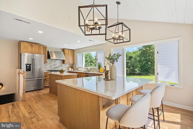 kitchen with visible vents, a center island, lofted ceiling, stainless steel appliances, and wall chimney exhaust hood