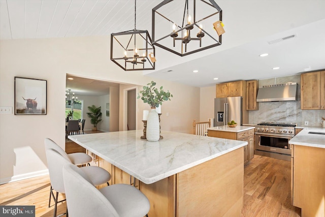 kitchen featuring a kitchen island, vaulted ceiling, premium appliances, range hood, and a notable chandelier