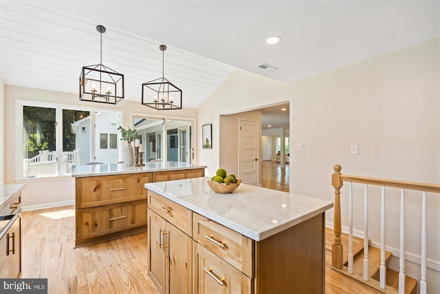 kitchen featuring visible vents, light wood-style flooring, a center island, vaulted ceiling, and hanging light fixtures