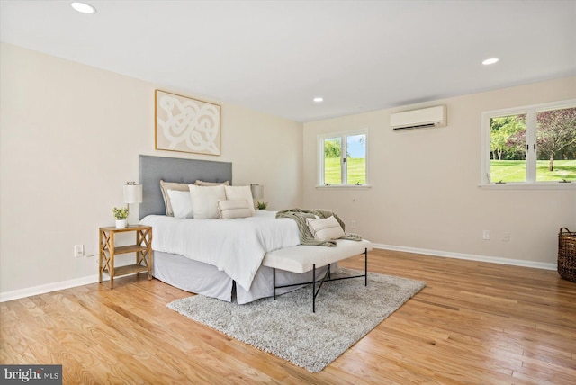 bedroom with recessed lighting, a wall mounted air conditioner, baseboards, and wood finished floors