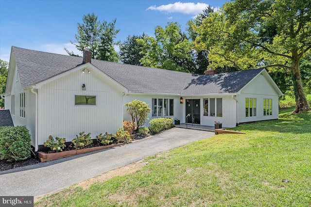 modern inspired farmhouse featuring a front lawn, roof with shingles, and a chimney