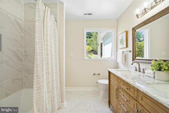 bathroom with visible vents, toilet, a sink, double vanity, and baseboards