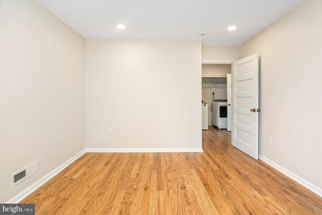 spare room with light wood-type flooring, visible vents, washer / clothes dryer, and baseboards