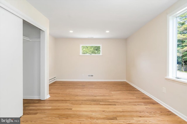 unfurnished bedroom featuring a baseboard radiator, multiple windows, and baseboards