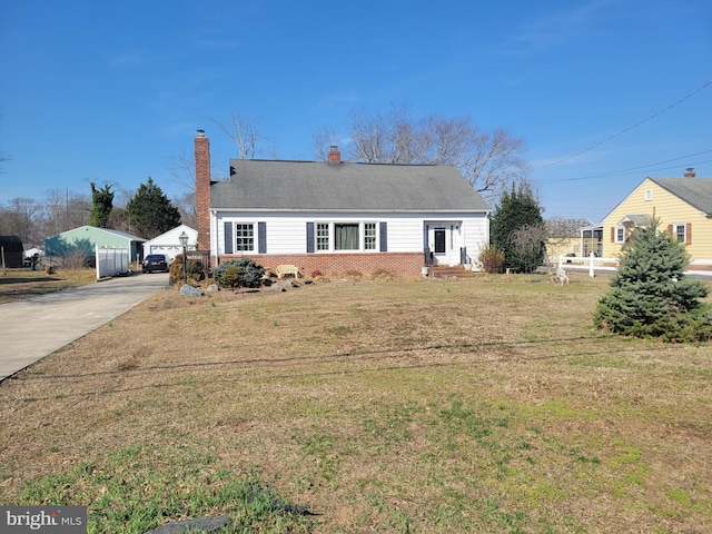 view of front of home featuring a front lawn, brick siding, driveway, and a chimney