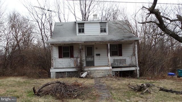 view of front facade featuring covered porch and a chimney