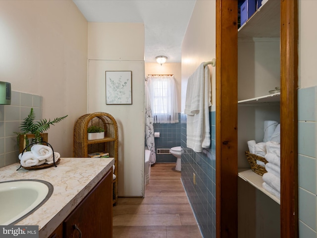 full bathroom with toilet, vanity, tile walls, and wood finished floors