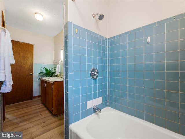 full bathroom with vanity, wood finished floors, wainscoting, tile walls, and shower / bathtub combination