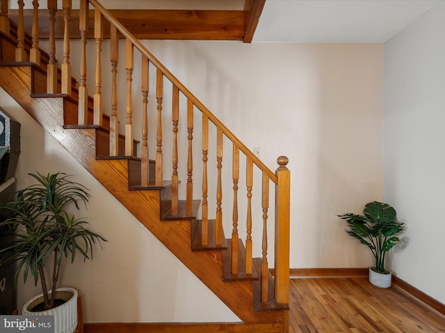 stairway with beam ceiling, baseboards, and wood finished floors