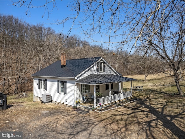 exterior space with central air condition unit, a porch, a chimney, and driveway