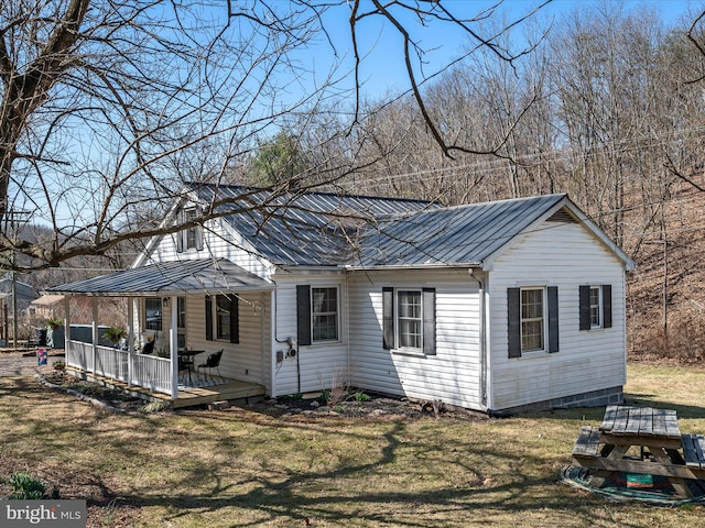 view of front of house with metal roof, a front yard, and a standing seam roof