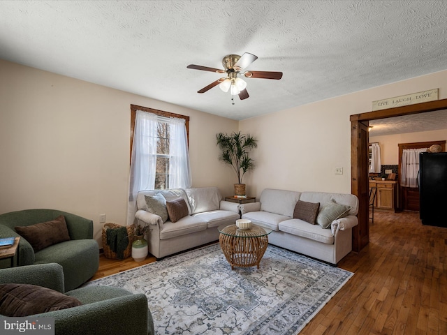 living room featuring dark wood finished floors, a textured ceiling, and a ceiling fan